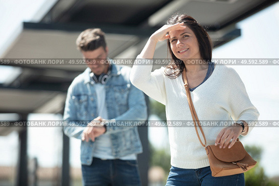 woman waiting for public transport shields eyes from the sun. Стоковое фото, агентство Ingram Publishing / Фотобанк Лори