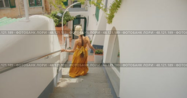 Woman walking down narrow stairs between buildings and gestures follow me in Italian city. Стоковое видео, видеограф Igor Tichonow / Фотобанк Лори