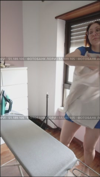 Woman wearing blue dress putting on white shirt. Стоковое видео, видеограф Константин Шишкин / Фотобанк Лори