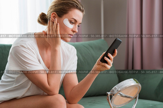 woman wearing eye mask patches using mobile phone. Стоковое фото, агентство Ingram Publishing / Фотобанк Лори
