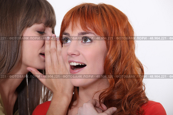 Woman whispering into another woman’s ear. Стоковое фото, агентство Ingram Publishing / Фотобанк Лори