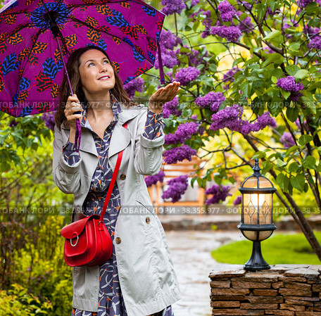 Woman with an umbrella in her hands walks in the spring rainy garden. Стоковое фото, фотограф Astroid / Фотобанк Лори