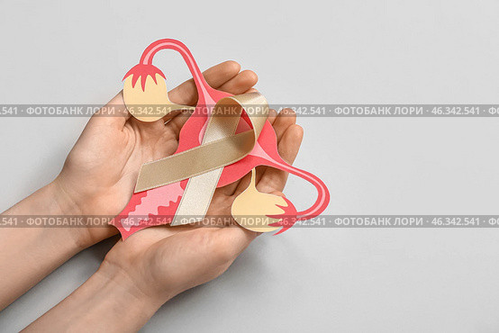 Woman with beige ribbon and paper uterus on light background. Cancer awareness concept. Стоковое фото, фотограф Pixel_shot / Фотобанк Лори