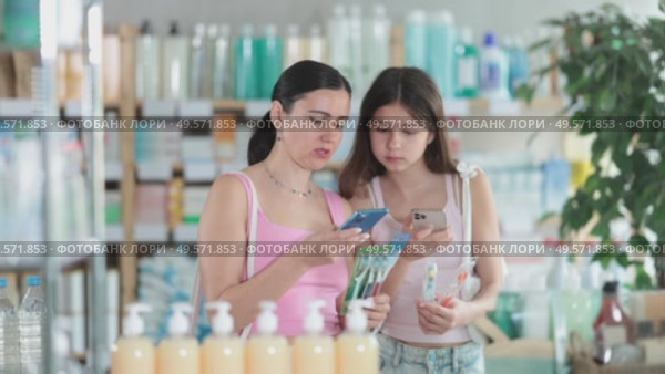 Woman with teen daughter in pharmacy scans QR code on toothbrush. Стоковое видео, видеограф Яков Филимонов / Фотобанк Лори