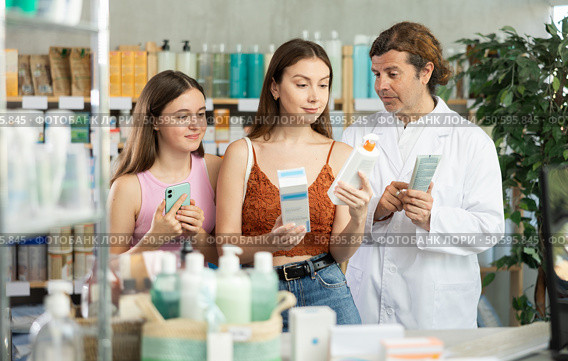 Woman with teen girl choosing and scan QR code cream at pharmacy. Стоковое фото, фотограф Яков Филимонов / Фотобанк Лори