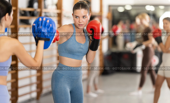 Woman works out strength and speed of boxing punch mitts with help of partner in boxing paws. Стоковое фото, фотограф Яков Филимонов / Фотобанк Лори