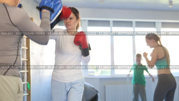 Woman works out strength and speed of boxing punch mitts with help of partner in boxing paws. Стоковое видео, видеограф Яков Филимонов / Фотобанк Лори
