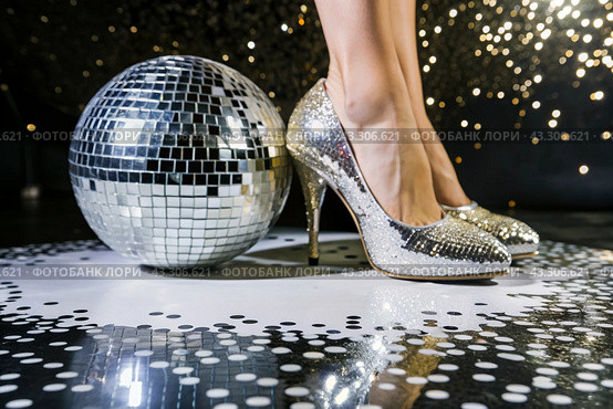 Women's legs in luxurious shiny pumps with heels at a party or disco on the background of a silver mirrored disco ball. The queen of the dance floor. Стоковое AI-изображение, AI-художник Photojuli / Фотобанк Лори