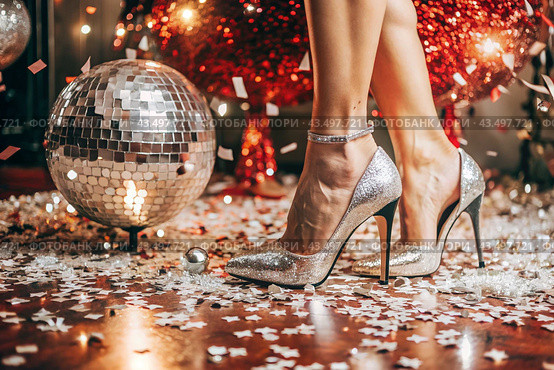 Women's legs in luxurious shiny pumps with heels at a party or disco on the background of a silver mirrored disco ball. The queen of the dance floor. Стоковое AI-изображение, AI-художник Photojuli / Фотобанк Лори