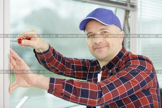 worker fasten the handle to a plastic window. Стоковое фото, агентство Ingram Publishing / Фотобанк Лори