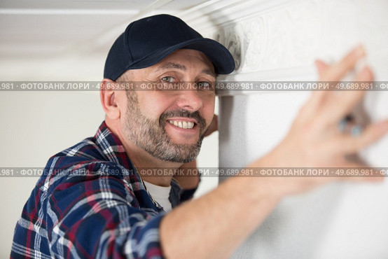 worker fixes the wood molding to the ceiling. Стоковое фото, агентство Ingram Publishing / Фотобанк Лори