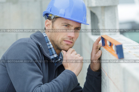 worker measures the curvature of the wall with a level. Стоковое фото, агентство Ingram Publishing / Фотобанк Лори