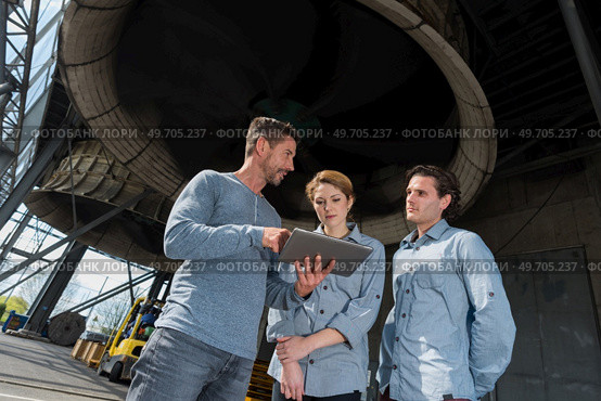 workers having a conversation underneath the factorys compressor. Стоковое фото, агентство Ingram Publishing / Фотобанк Лори