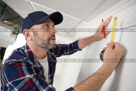 workman measuring ornate ceiling cornice. Стоковое фото, агентство Ingram Publishing / Фотобанк Лори