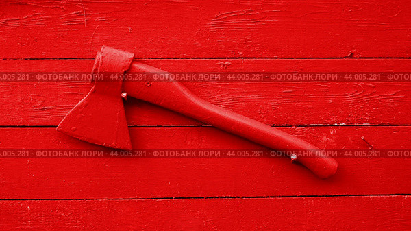 Яркий символ пожарной безопасности красный пожарный топор на фоне раскрашенного деревянного щита из досок помогающего рубить и тушить пожар. Стоковое фото, фотограф Марина Юферова / Фотобанк Лори