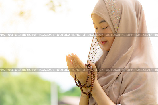 Young Adult teenager Woman making Duas for Muslim god blessing prayer. Стоковое фото, агентство Ingram Publishing / Фотобанк Лори