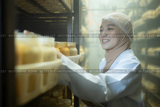 Young asian muslim female scientist doing research at a mushroom factory, examining mushroom leavening agent in a sterile and temperature-controlled room. Стоковое фото, агентство Ingram Publishing / Фотобанк Лори