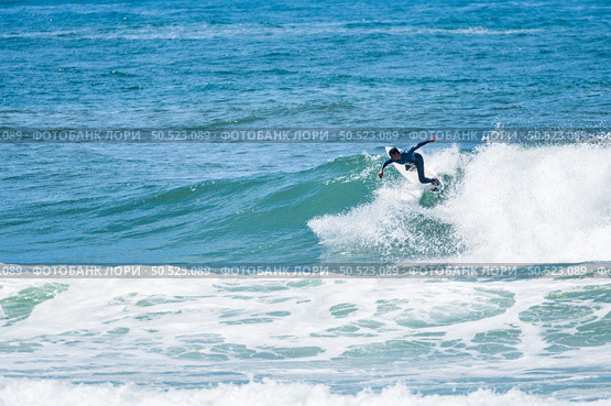 Young athletic surfer rides the wave in Furadouro Beach in Ovar, Portugal. Стоковое фото, агентство Ingram Publishing / Фотобанк Лори