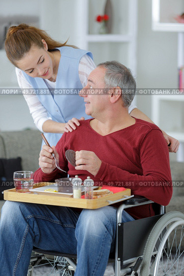 young beautiful nurse helpping disabled elder man at home. Стоковое фото, агентство Ingram Publishing / Фотобанк Лори