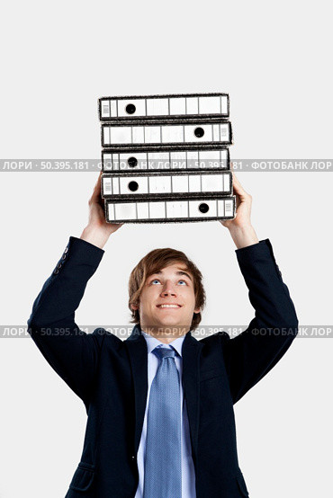 Young business man carrying a bunch of folders. Стоковое фото, агентство Ingram Publishing / Фотобанк Лори