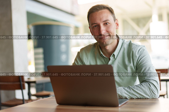 Young businessman sitting in cafe working with laptop computer. Стоковое фото, фотограф Сергей Толмачёв / Фотобанк Лори