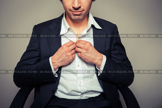 Young businessman sitting in office chair is buttoning his shirt. Стоковое фото, агентство Ingram Publishing / Фотобанк Лори