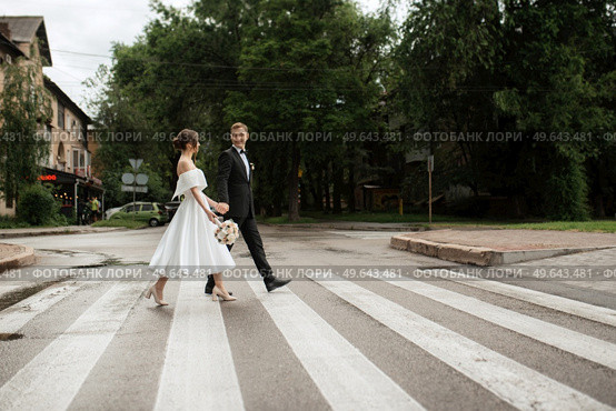 young couple bride and groom in a white short dress walking in the rain. Стоковое фото, агентство Ingram Publishing / Фотобанк Лори