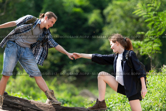 Young couple hiking in the forest with backpacks and trekking poles. Стоковое фото, агентство Ingram Publishing / Фотобанк Лори