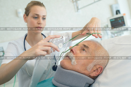 young female anesthetist putting oxygen mask on senior patient. Стоковое фото, агентство Ingram Publishing / Фотобанк Лори