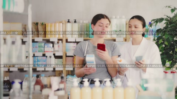 Young girl choosing cream or skin care product in pharmacy and scan QR code on label, young asian woman pharmacist consulting and offering variety of goods to customer. Стоковое видео, видеограф Яков Филимонов / Фотобанк Лори