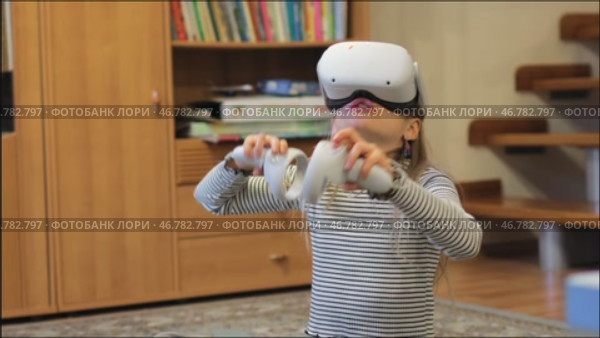 Young girl experiencing virtual reality with headset and motion controllers at home. Стоковое видео, видеограф Дмитрий Наумов / Фотобанк Лори