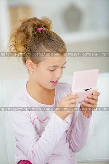 Young girl using a portable console. Стоковое фото, агентство Ingram Publishing / Фотобанк Лори