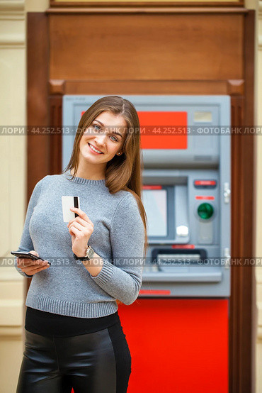 Young happy brunette woman withdrawing money from credit card at ATM. Стоковое фото, фотограф Андрей Аркуша / Фотобанк Лори