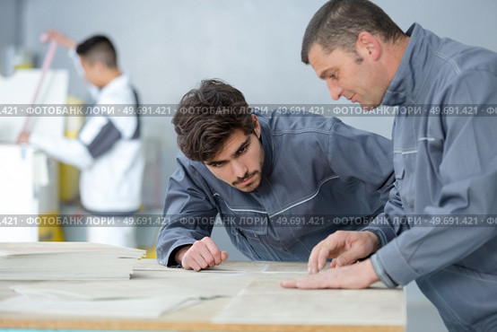 young male decorator watching supervisor demonstrating technique. Стоковое фото, агентство Ingram Publishing / Фотобанк Лори