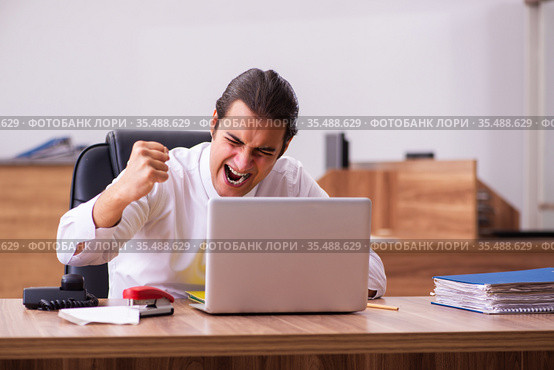 Young male employee stapling paper in the office. Стоковое фото, фотограф Elnur / Фотобанк Лори