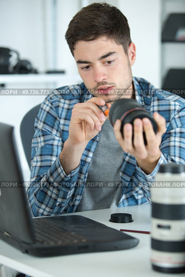 young male technician working on dismantled camera lens. Стоковое фото, агентство Ingram Publishing / Фотобанк Лори