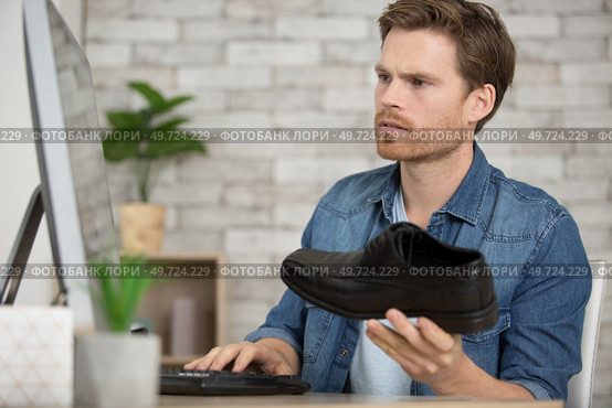 young man checking shoe reference at home. Стоковое фото, агентство Ingram Publishing / Фотобанк Лори