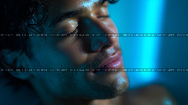 Young man enjoys a moment of relaxation with soft blue lighting in a serene environment at night. Стоковое AI-изображение, AI-художник Сергей Толмачёв / Фотобанк Лори
