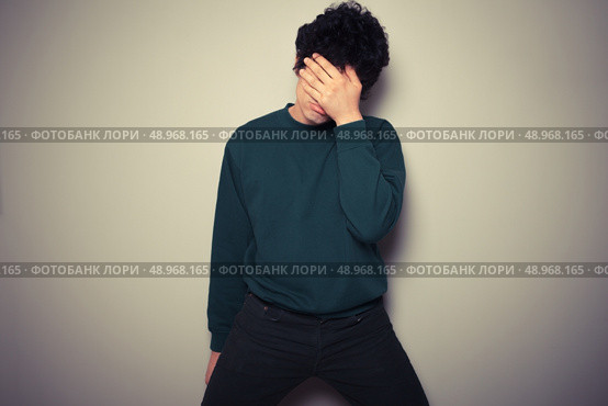 Young man is hiding his face in the palms of his hands. Стоковое фото, агентство Ingram Publishing / Фотобанк Лори