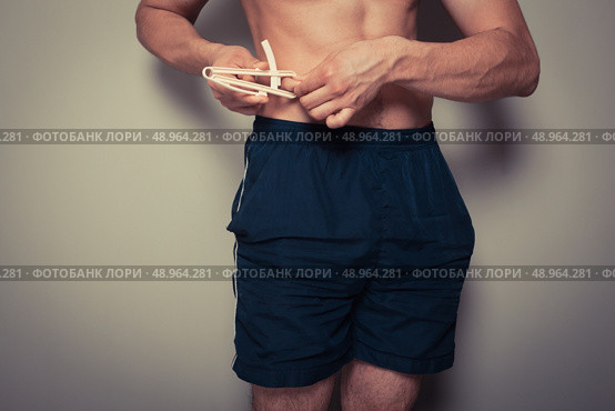 Young man is measuring his body fat with calipers. Стоковое фото, агентство Ingram Publishing / Фотобанк Лори