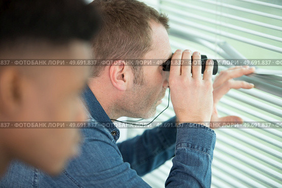 young man looks out the window with binoculars close-up. Стоковое фото, агентство Ingram Publishing / Фотобанк Лори