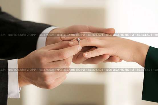 Young man putting engagement ring on fiancee's finger. Стоковое фото, фотограф Pixel_shot / Фотобанк Лори