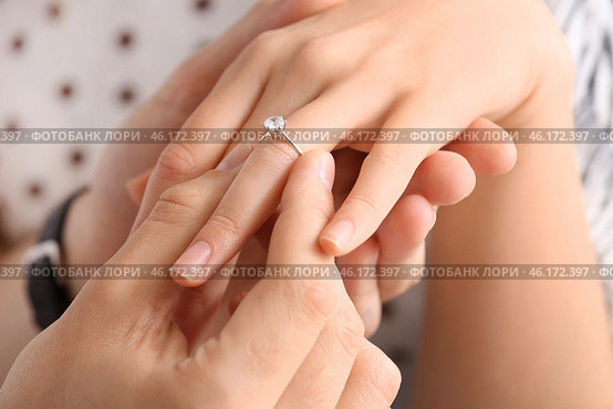 Young man putting ring on finger of his fiancee after marriage proposal, closeup. Стоковое фото, фотограф Pixel_shot / Фотобанк Лори