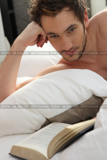 Young man reading a book in bed. Стоковое фото, агентство Ingram Publishing / Фотобанк Лори