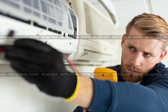 young man repairing air conditioner indoors. Стоковое фото, агентство Ingram Publishing / Фотобанк Лори