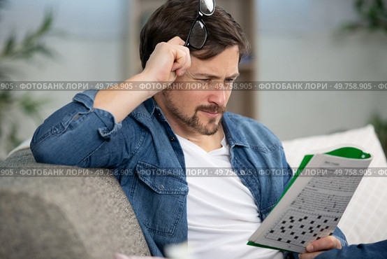 young man sitting doing a crossword puzzle. Стоковое фото, агентство Ingram Publishing / Фотобанк Лори