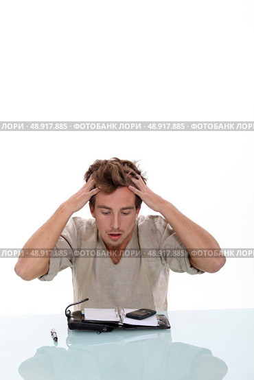 Young man tearing his hair out over the contents of his personal organizer. Стоковое фото, агентство Ingram Publishing / Фотобанк Лори