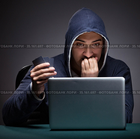 Young man wearing a hoodie sitting in front of a laptop computer. Стоковое фото, фотограф Elnur / Фотобанк Лори