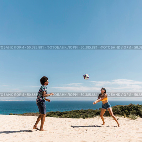 young multicultural couple playing volleyball beach. Стоковое фото, агентство Ingram Publishing / Фотобанк Лори