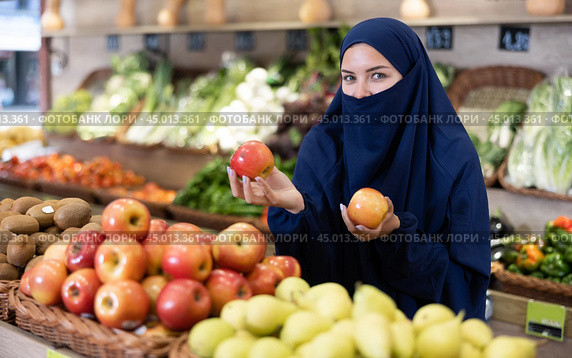 Young Muslim woman in niqab choosing apples in store. Стоковое фото, фотограф Яков Филимонов / Фотобанк Лори